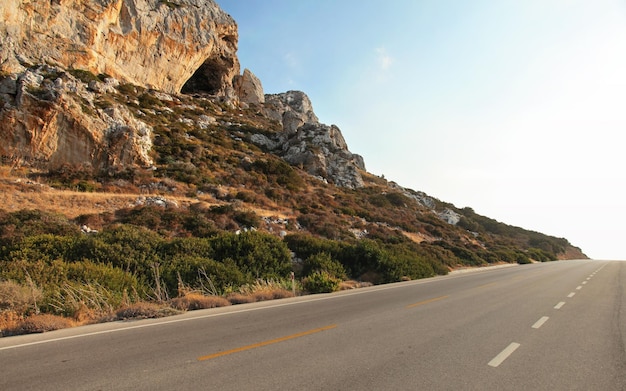 Evening sun shines on sharp rocks by the asphalt road - typical scenery on Karpasia peninsula in northern Cyprus.