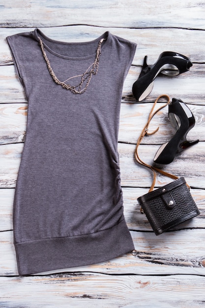 Evening top with black heels. Gray top and chain necklace. Designer clothes on boutique showcase. Dark colors of charm.