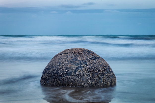 Photo evening view of perfect spherical stone at moeraki boulders beach, new zealand