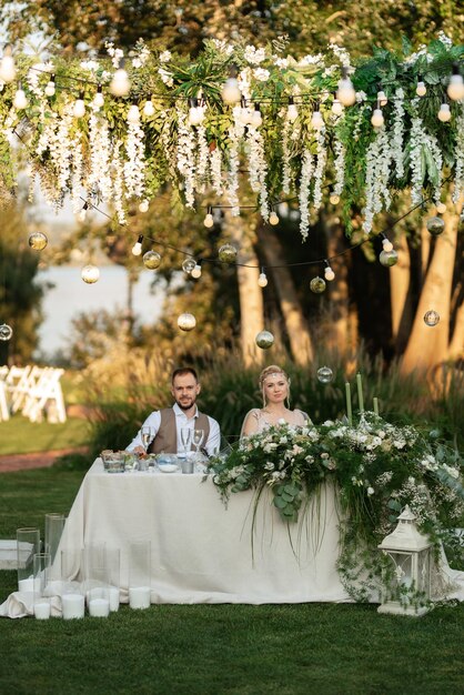 Photo evening wedding family dinner in the forest with light bulbs and candles