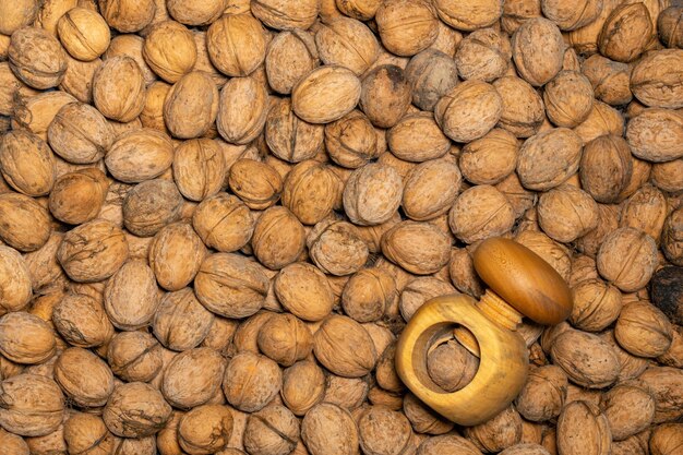 Evenly spaced walnuts laid out to fill the frame with a wooden nutcracker