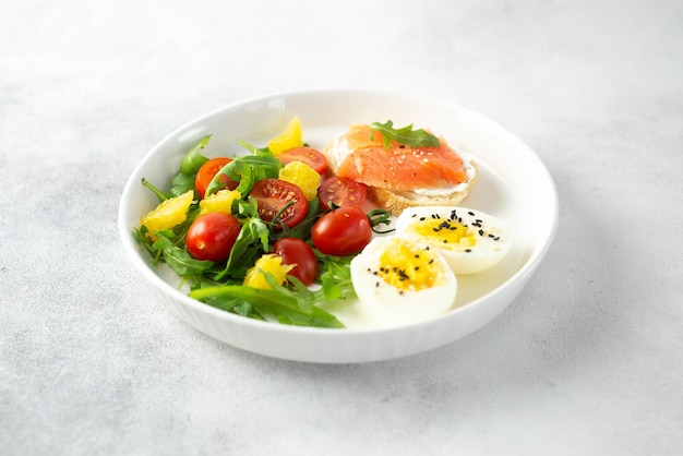 Evenwichtig ontbijt met vissandwich gekookt ei en groenten op grijze achtergrond
