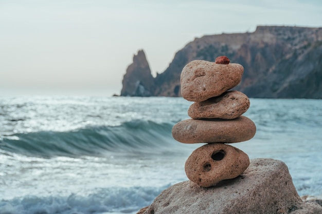 Evenwichtige kiezelpiramide op het strand op een zonnige dag zeeschuim op de achtergrond selectieve focus zen