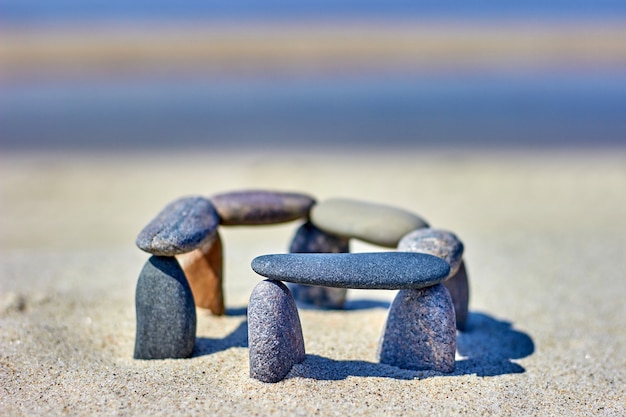 Evenwichtige kiezelstenen aan de zandige kust. Stenen worden gestapeld op het strand. Little Stonehenge