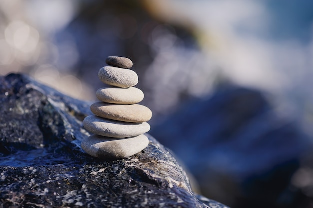 Evenwichtige stenen piramide aan de oever van blauw water. spa stenen behandeling scène, zen-achtige concepten. kiezelstenen toren aan de kust.