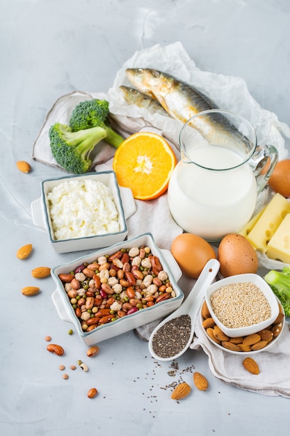 Evenwichtige voeding, gezond eten concept. Assortiment van voedselbronnen rijk aan calcium, bonen, zuivelproducten, sardines, broccoli, chiazaden, amandelen op een keukentafel