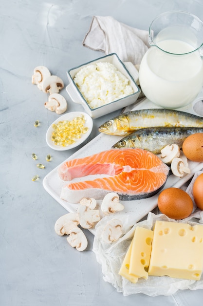 Evenwichtige voeding, gezond eten concept. assortiment van voedselbronnen rijk aan vitamine d, zalm, zuivelproducten, melk, eieren, kaas, champignons, sardines op een keukentafel