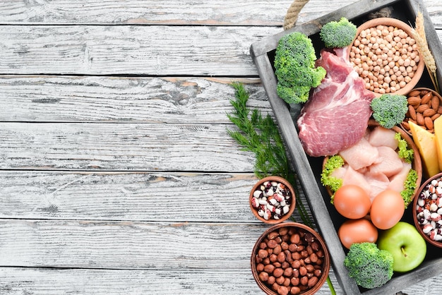 Evenwichtige voeding voedsel achtergrond vlees kipfilet broccoli bonen kaas eieren tarwe op een witte houten achtergrond