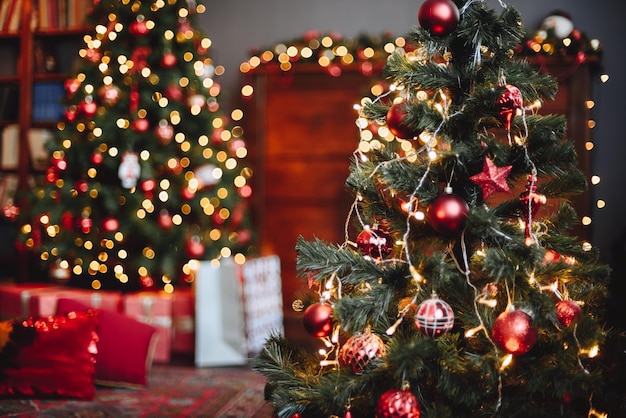 L'albero di natale sempreverde è decorato con giocattoli rossi e ghirlande luminose ghirlande bokeh gialle