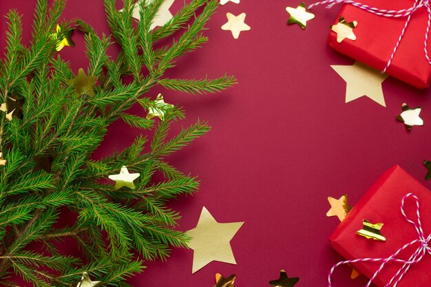 Evergreen tree, red gift boxes and  starry confetti on a red background with free space for text