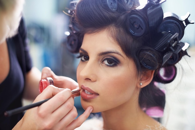 Photo every girl loves to be pampered a young model at the hair salon having lipstick applied