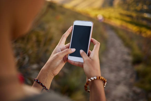 Ogni amante della natura dovrebbe scaricare questa app foto ritagliata di una donna che usa il suo cellulare durante un'escursione