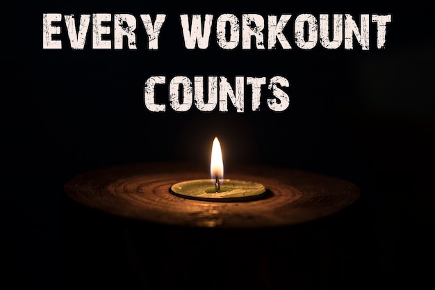 Every workount counts - white candle with dark background - in a wooden candlestick.