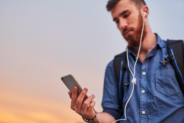 Everything he needs is right in his hand Low angle shot of a handsome young man listening to music on his cellphone while walking through the city