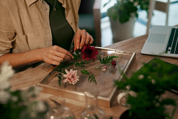 Foto tutto sta andando a posto perfettamente inquadratura ritagliata di un fiorista irriconoscibile che decora e preme i fiori in una cornice da parete all'interno del suo negozio