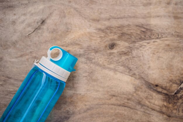 Everything for sports turquoise blue shades on a wooden background Yoga mat sport shoes sportswear and bottle of water Concept healthy lifestyle sport and diet Sport equipment Copy space