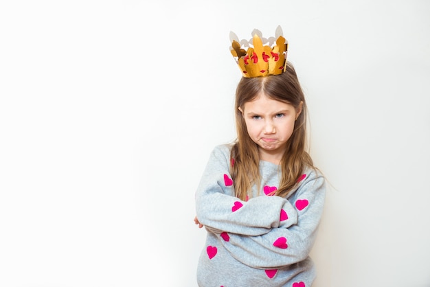 Evil child girl with a crown on a white