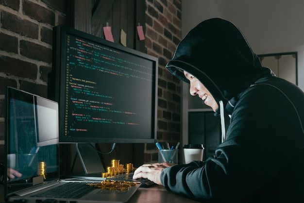 Hacker uomo malvagio che esamina il sistema online del computer e utilizza il virus dei dati di digitazione della tastiera nelle informazioni personali online globali rubano bitcoin gold