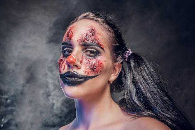 Evil psycho clown makeup looks especially creepy in a smoke over dark background.