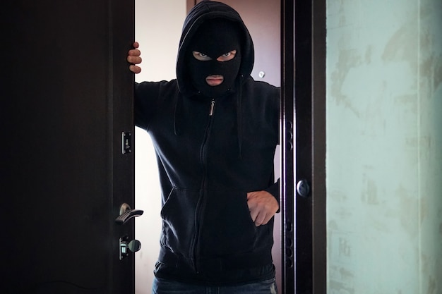 Evil threat to Rob broke into private ownership. Breaking into an apartment. Maniac went into the house. The concept of crime and violence. Open door to a stranger. A gun or a knife in your pocket