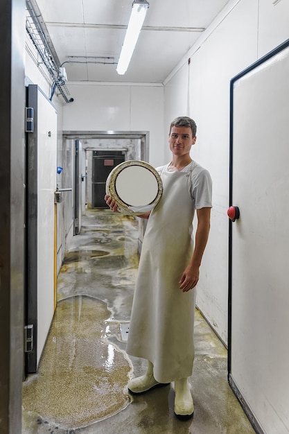 Evillers, france - august 31, 2016: cheese maker holding a\
wheel of cheese at franche comte dairy in france