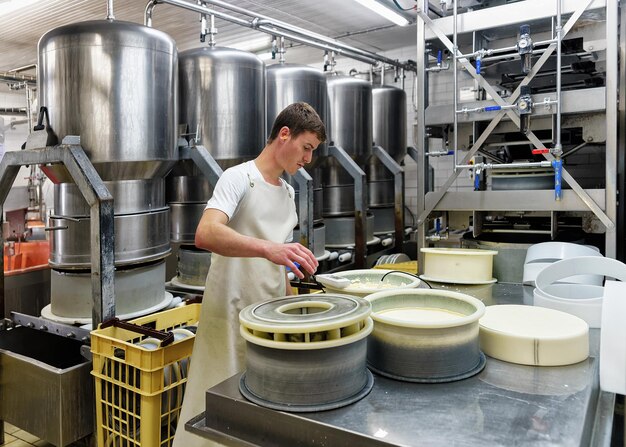 Evillers, France - August 31, 2016: Cheese maker puts Gruyere de Comte Cheese in the forms at the dairy in Franche Comte, Burgundy, in France.