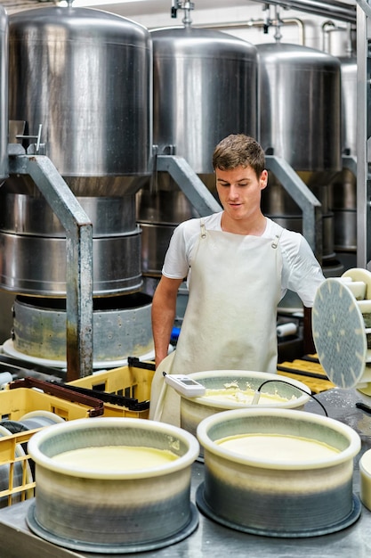 Evillers, France - August 31, 2016: Cheese-maker putting young Gruyere de Comte Cheese in the forms at dairy in Franche Comte, Burgundy, in France.