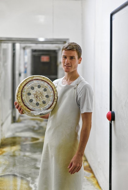 Эвиллерс, Франция - 31 августа 2016 г.: Рабочий держит колесо сыра Грюйер де Конт на складе маслозавода Франш Конт во Франции