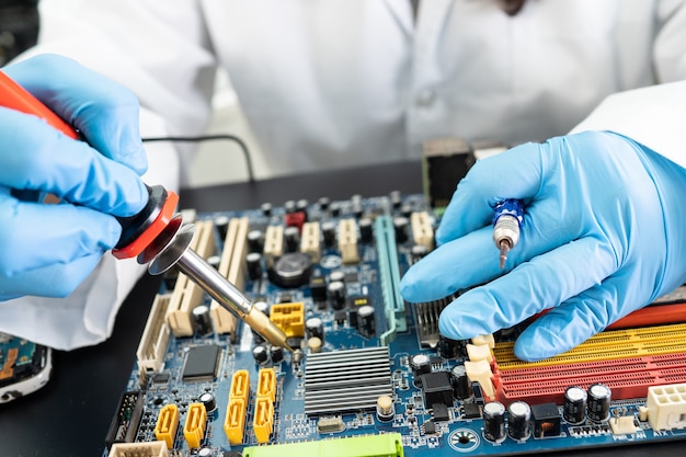 Ewaste technician repairing inside of hard disk by soldering iron