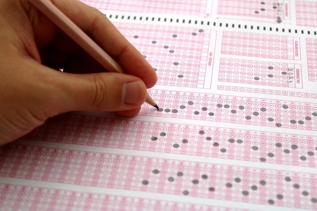 Photo exam a hand taking a test with a pencil over an optical reader future anxiety uncertainty