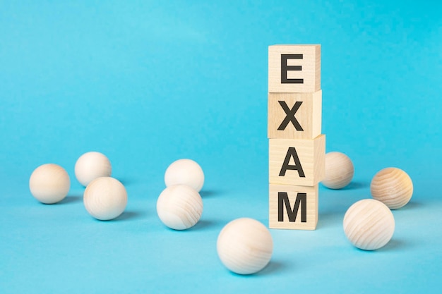 EXAM text on wooden block with bright blue background