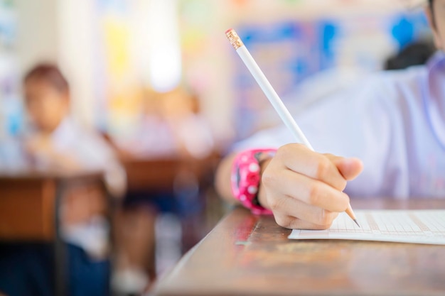 Exam with uniform school student concept Close up hand student is taking exam and writing answer in classroom for education test