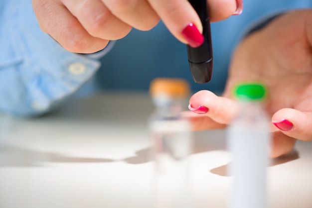 Examine sugar. Blocking sugar testing, woman finger lancet punctures. Close up.