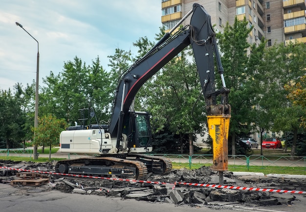 Фото Экскаватор, разрушающий бетонное дорожное покрытие с помощью гидромолота при ремонте дорожных работ