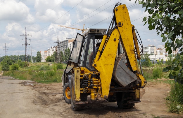 Excavator on a construction site against the background of the sky. Heavy machinery at work. A large yellow construction vehicle at a construction site. Industrial image.