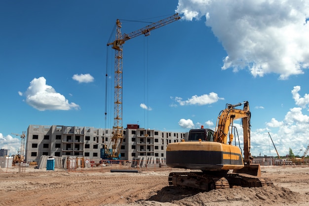 Photo excavator at a construction site against the background of a tower crae