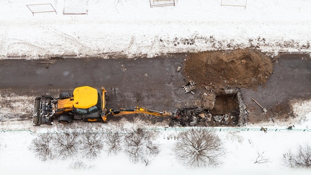 Photo excavator digging road to change sewer pipes