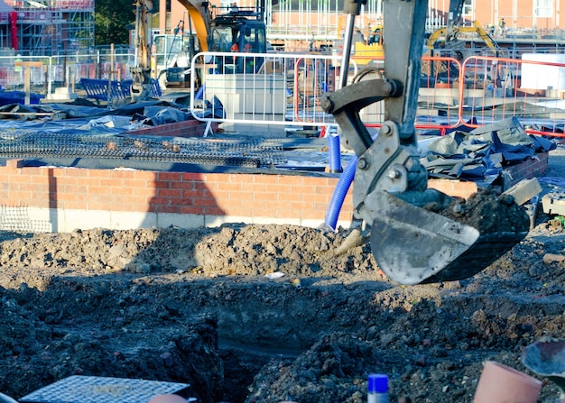 Экскаватор копает траншею для дренажа и обслуживания дома на новой площадке строительства жилья