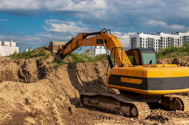 掘削機は、住宅の建設のための基礎ピットを掘ります。バックグラウンドで新しい住宅の建物。建設生産。発掘。