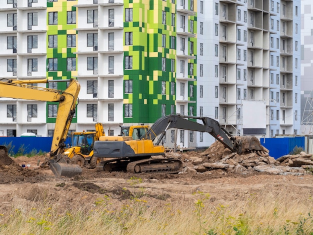 Экскаватор роет землю под фундамент и строительство нового дома.