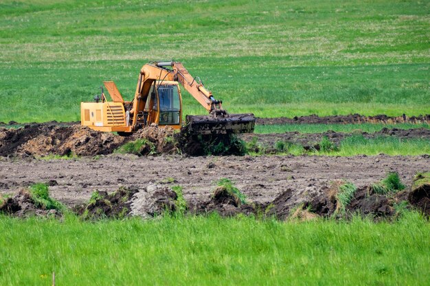 Photo an excavator digs the ground to lay pipes