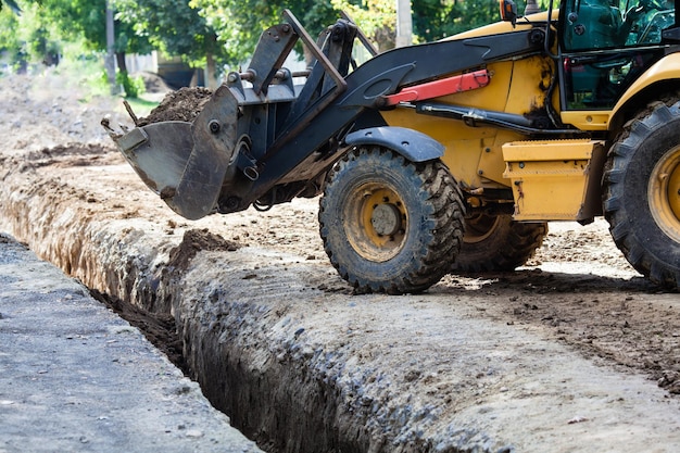 The excavator falls asleep a trench. Construction in a suburban area