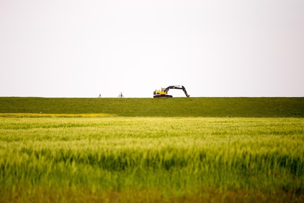 Photo excavator on grassy field against clear sky