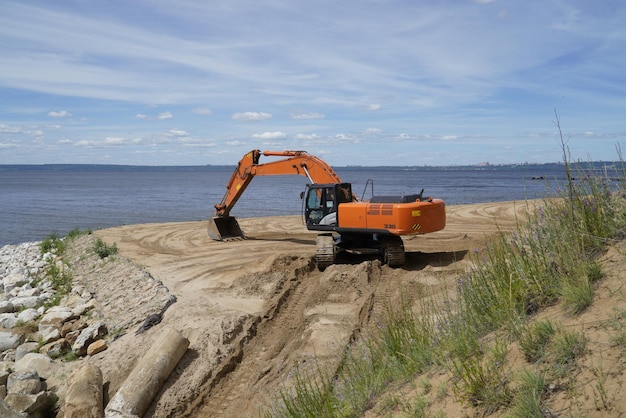 The excavator levels the sandy bank of the Volga River Ulyanovsk Russia