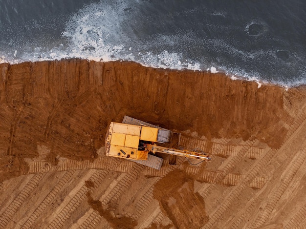 Excavator machine doing an earthwork on a shoreAerial photography