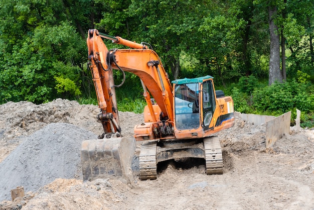 L'escavatore esegue i lavori di scavo sul cantiere. il trattore giallo scava il terreno