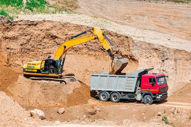 An excavator in a sand pit loads a dump truck with sand
extraction of sand in an open pit natural building materials