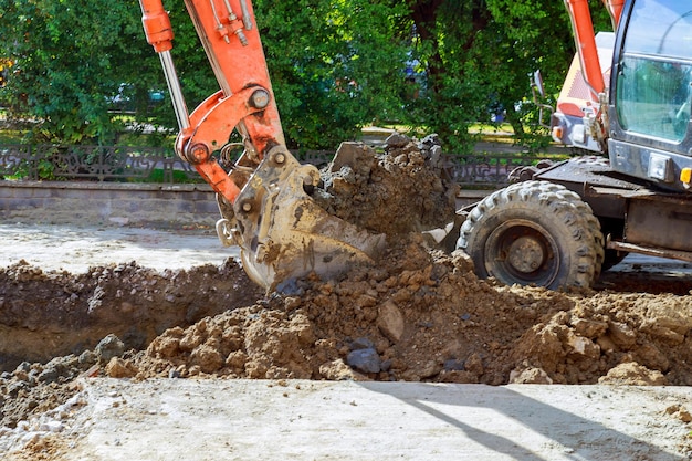 Экскаватор на песочнице во время земляных работ копает дорогу