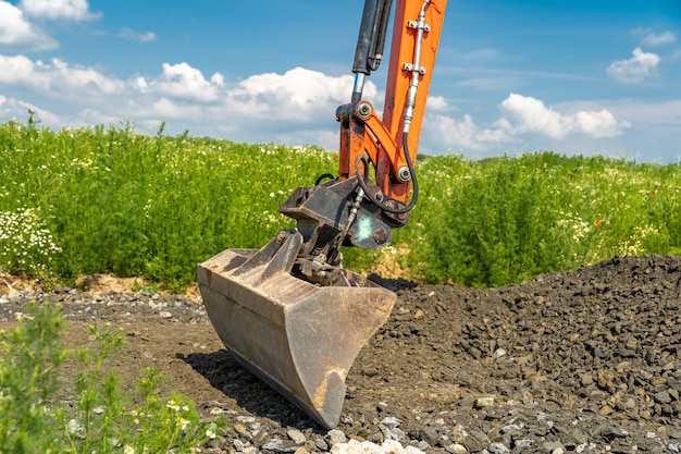 The excavator spreads the ground on the field.