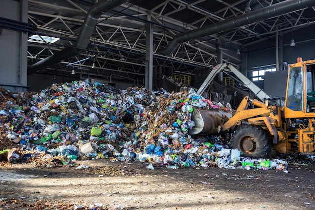 Excavator stacks trash in big pile at sorting modern waste recycling processing plant Separate and sorting garbage collection Recycling and storage of waste